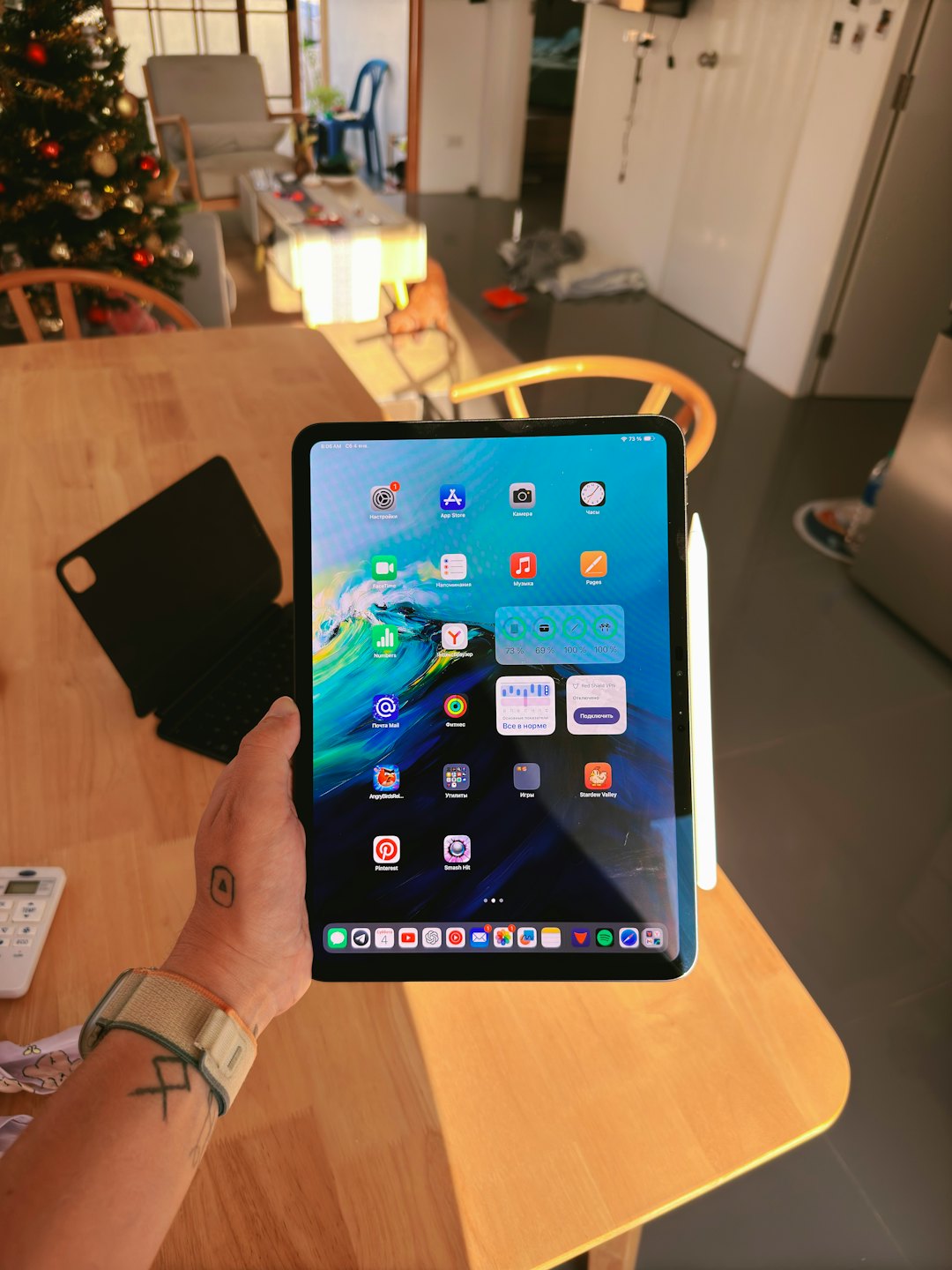 Person using a tablet with apps and Apple Pencil on a table.