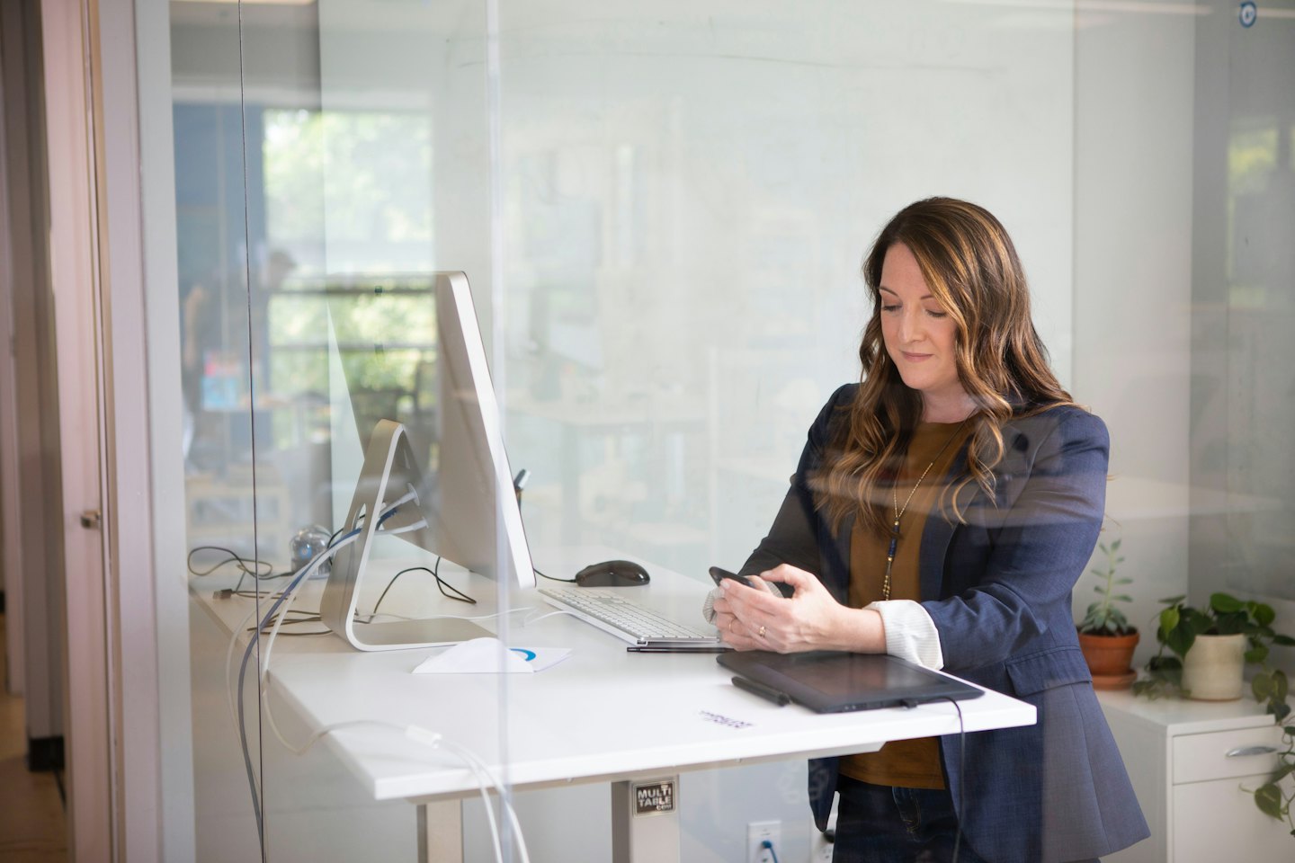 Woman using smartphone at a modern office desk.
