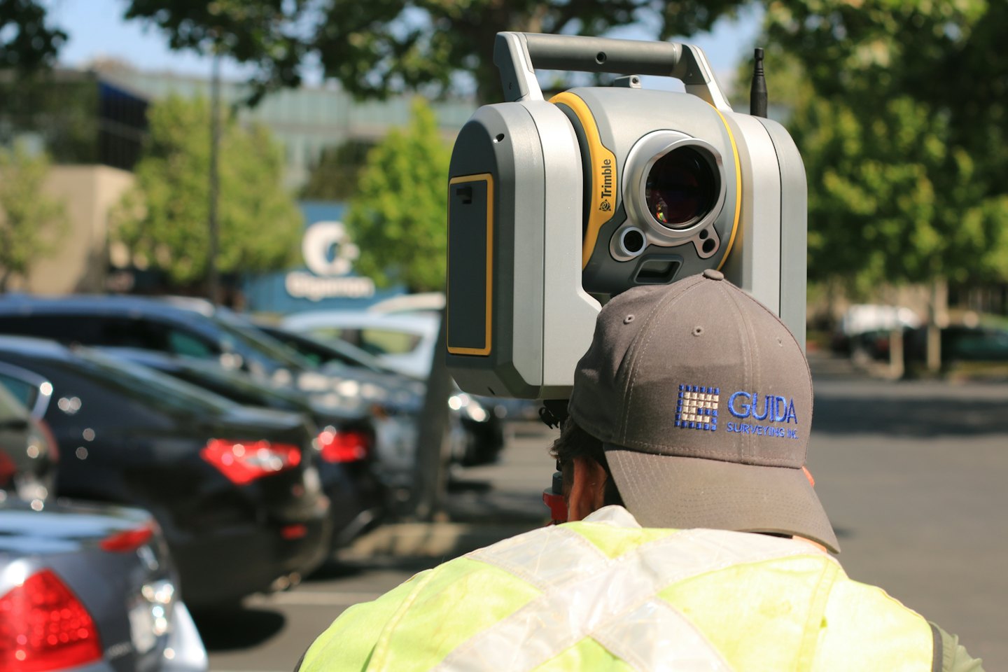 Surveyor operates Trimble instrument in a parking lot.